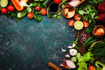 Fresh healthy food cooking or salad making ingredients on dark background with rustic wooden board....