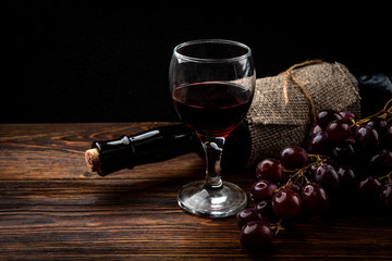 Red wine and grape on dark wooden background.