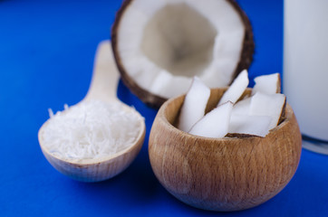Natural coconut milk, coconut shavings, coconut chips on a blue background. The concept of healthy food.
