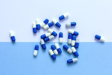White and blue medicine capsules in the palm of your hand.