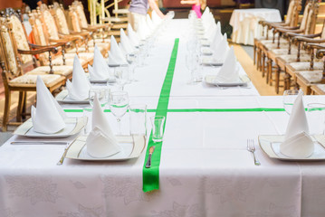 Long served table with plates, glasses, napkins and chairs