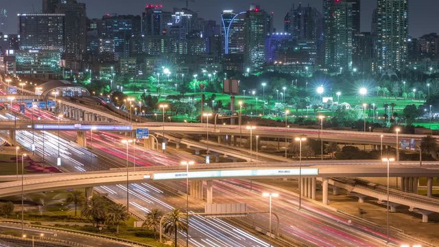 Dubai Golf Course with a cityscape of Gereens and tecom districts at the background aerial night timelapse. Traffic on sheikh zayed road with junction