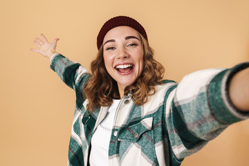 Photo of pretty happy woman in knit hat taking selfie and laughing