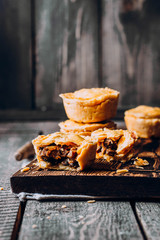 Fresh Traditional Australian meat mini pie on the wooden board on table background, closeup with copy space, rustic style - 324197415