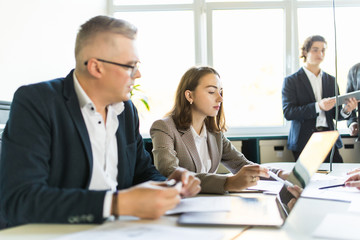 Group of young diverse business people working and communicating while sitting at the office desk