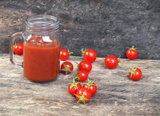 tomato juice in glass jar and tomatoes on wooden table background, drink for health 