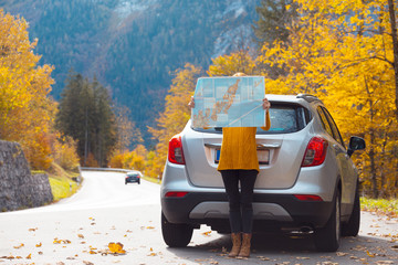 girl with a map is standing near the car