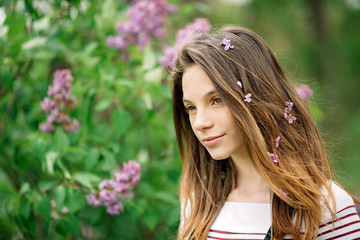 Beautiful young girl walking in the garden of a blooming lilac on a summer day. Copy space.
