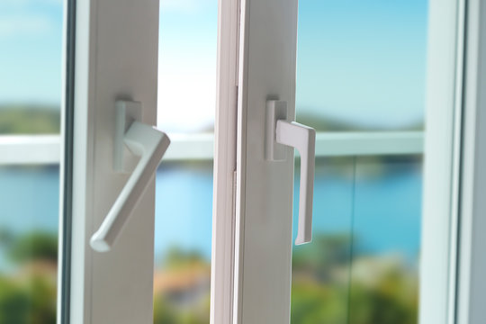 Sliding door of a balcony. Close-up of the lock on the door with and nice landscape of background. White PVC door and security glass.