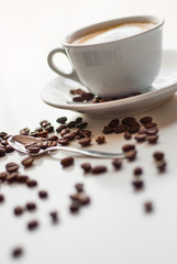 Taza de café sobre fondo blanco con granos de café