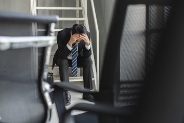 Stressed businessman sitting at stairway in office, Desperate for work. Stress business concept.