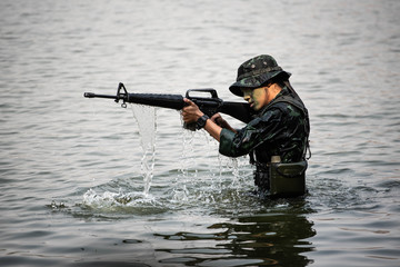 A woman soldier with gun in the river of Battlefield/Army training/military uniform