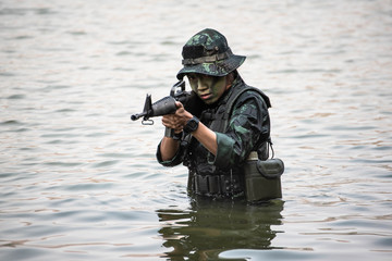 A woman soldier with gun in the river of Battlefield/Army training/military uniform