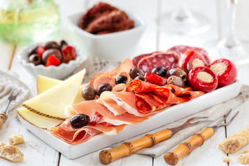 Delicious meat platter with cheese, spicy olives and stuffed cherry pepper served as an appetizer...