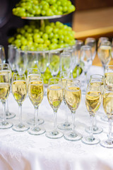 Glasses of champagne waiting for guests, grapes on the background