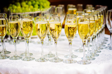 Glasses of champagne waiting for guests, grapes on the background, rustic toned