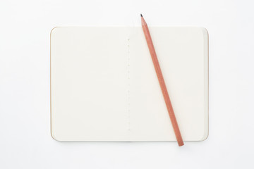 Top view of closed stitch blank recycled paper cover notebook with pencil on white background.