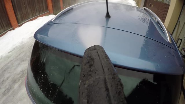 A jet of strong water pressure washes away the dirt from the roof of the car