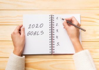 Female hands writing future 2020 goals in spiral notepad