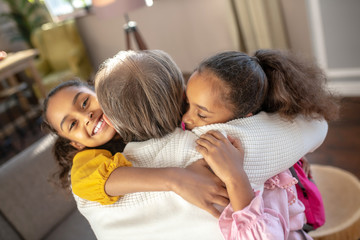 Bearded granddad hugging his granddaughters and feeling amazing