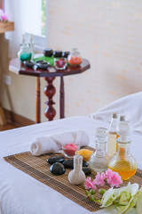 Obraz na płótnie Canvas Spa treatment set and aromatic massage oil on bed massage. Thai setting for aroma therapy and massage with flower on the bed, relax and healthy care.