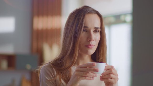 Satisfied woman drinking tea on kitchen. Lady enjoying cup of coffee at home