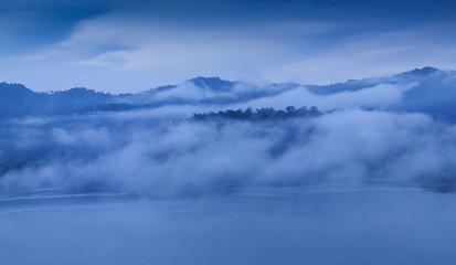 Fototapeta na wymiar view of soft mist moving on top hill with mountain and cloudy sky background, Khao Sok National Park, Surat Thani, southern Thailand.