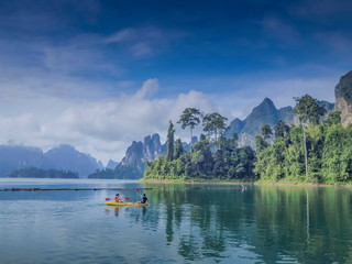 Lake view of tourists kayaking in the lake around with green forest, limestone mountains and cloudy...