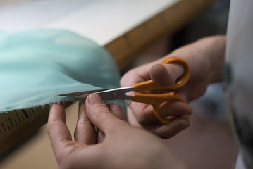 girl cutting textile with scissors
