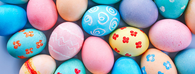 Fototapeta na wymiar Colorful Easter eggs dyed by colored water with beautiful pattern on a pale blue background, design concept of holiday activity, top view, full frame.