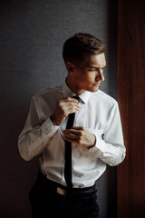 Handsome groom on a black suit with black glasses