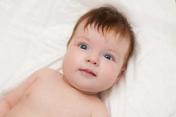 Newborn child relaxing in bed.