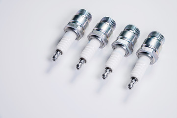 Subject shooting on a gray background. new four spark plugs, spare parts for a gasoline engine. The...