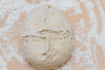 Prepared kneaded dough on a wooden table at home