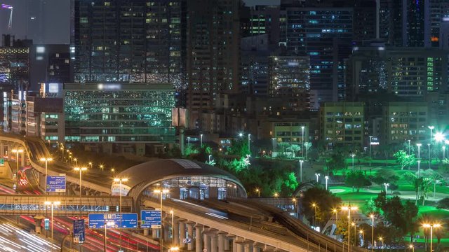 Dubai Golf Course with a cityscape of Gereens and tecom districts at the background aerial night timelapse. Traffic on sheikh zayed road with metro station