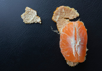 Top view, orange peeled by hand, placing orange on the floor. Healthy fresh orange. on black. Healthy diet concept. Peeled oranges placed on black floor. Concept difference in same place