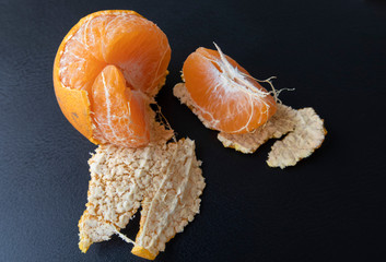 Top view, orange peeled by hand, placing orange on the floor. Healthy fresh orange. isolated on black. Healthy diet concept. Peeled oranges placed on black floor. Concept difference in same place
