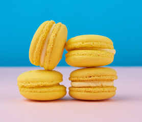 stack of baked round yellow lemon macarons on a blue-pink background