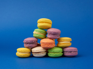 stack of multi-colored round baked macarons cakes on a dark blue background