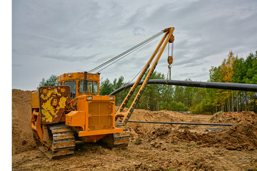 Pipelayer tractor lifts a pipe