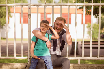 Obraz premium Smiling Young father and his son who is sitting in a lap, hugging and posing for a camera.