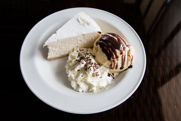 Top view image of cheese cake, ice cream, and whipped cream.