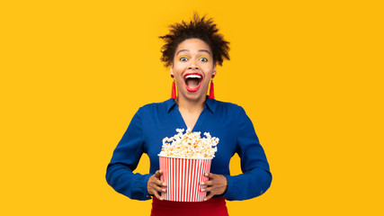 Millennial black girl with popcorn shaking popcorn