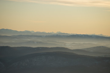 Beautiful view of the mountain range partially covered with snow just before sunset. Partly orange sunset sky