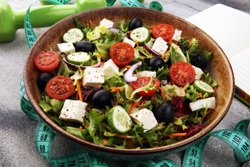 Authentic fresh salad in a stone cup with dumbbells excercise equipment, measuring tape on table. healthy lifestyles, good health Concept with fresh ingredients