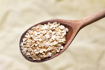 Oat flakes on wooden spoon. Healthy breakfast portion empty copy space background.