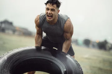 Tuinposter Strong sportsman doing a tire flip exercise © Jacob Lund