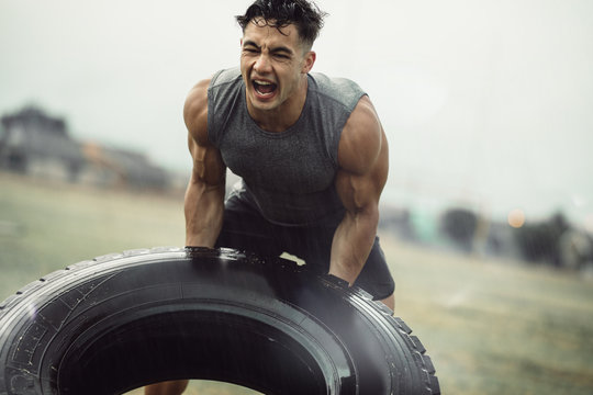 Strong sportsman doing a tire flip exercise