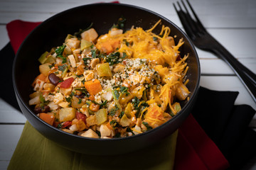 A bowl of warm salad  containing mixed root vegetables, beans, kale and chipotle corn salsa