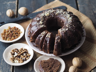 Festive homemade cakes. Round chocolate muffin, large sponge cake or cake with chocolate icing on a dark wooden background. Place for text, side view.